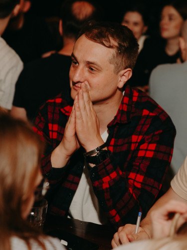 Молодий чоловік сидить за столом у компанії партнерів по команді.