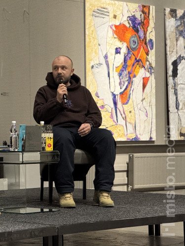 Двоє людей сидять на кріслах на сцені.