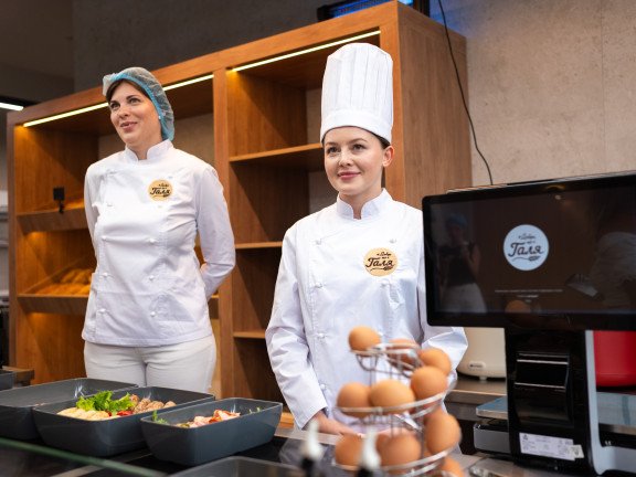 Кухарі пекарі жінки у білій формі на касі закладу харчування