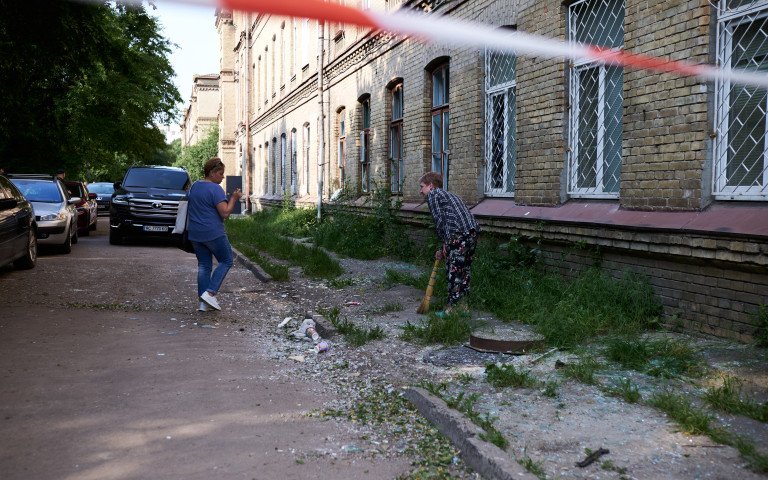 люди прибирають скло після ворожої атаки
