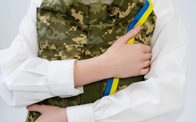 жінка пригортає до себе військову форму