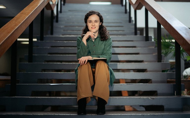 кучерява жінка сидить на сходах