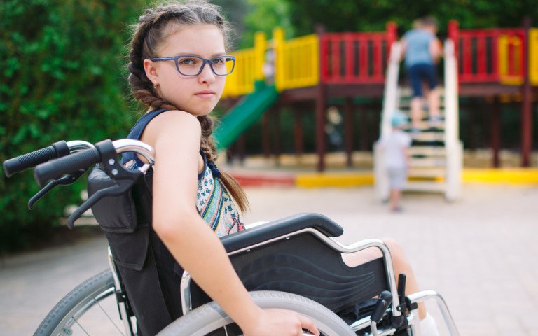 дівчинка на кріслі колісному на дитячому майданчику