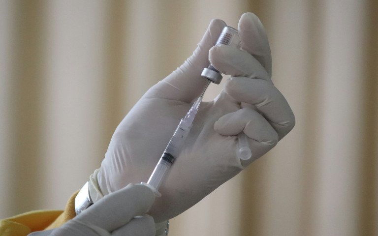 лікар в білих рукавичках готується зробити вакцинацію