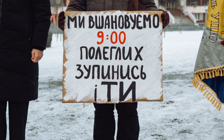 людина в темному одязі тримає плакат