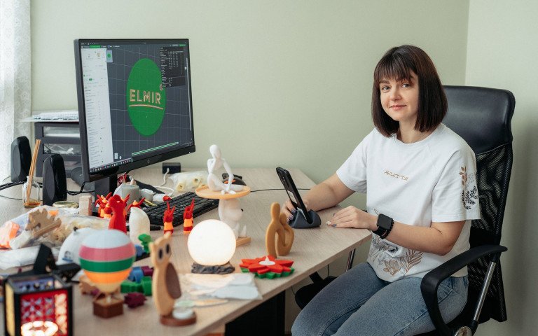 Жінка за комп'ютером з 3D-світильниками на столі.