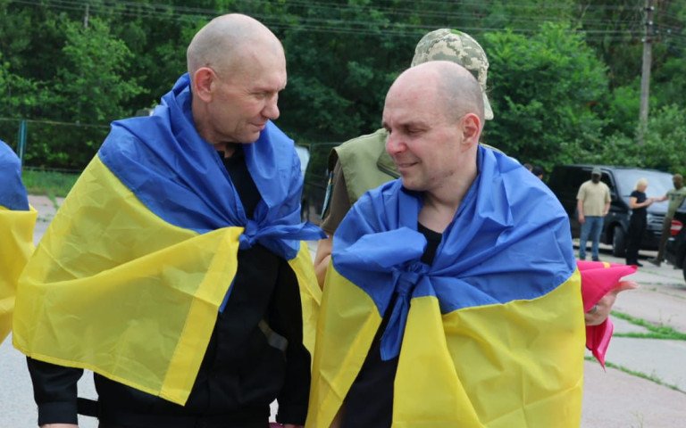 люди з синьо-жовтими прапорами на плечах