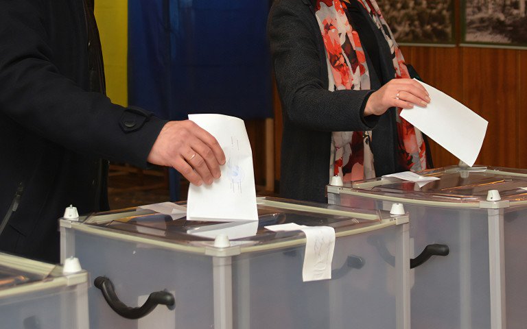 Урни для голосування. Чоловік і жінка кидають бюлетені в урни для голосування.