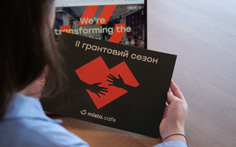 Грантовий сезон misto.cafe. Жінка тримає конверти в руках.