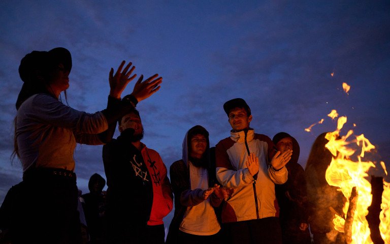 Остання ватра на Volyn Debate Camp під Луцьком. 2025 рік. Молодь стоїть біля ватри на фоні темно-синього неба.