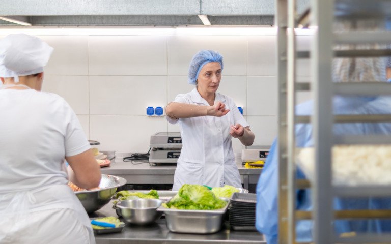 Жінки у білій формі на промисловій кухні.