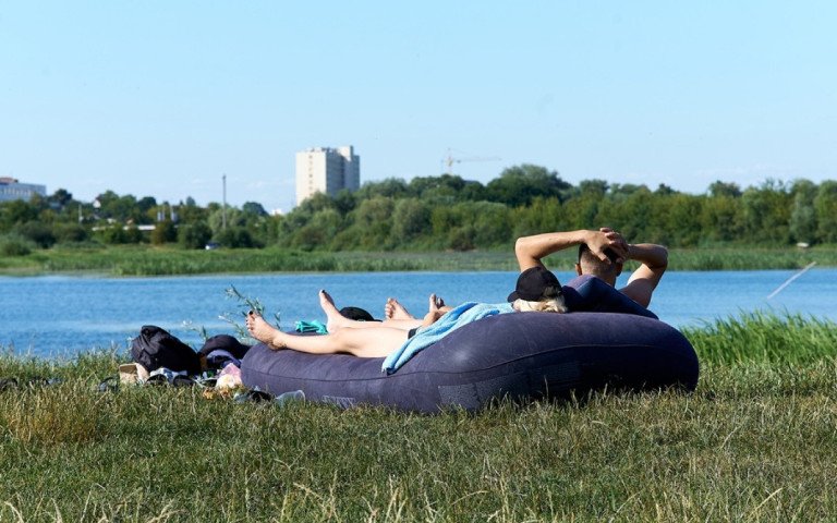 люди біля водойми лежать на матраці