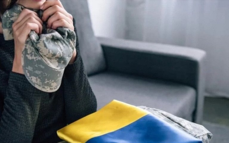 жінка з формою військового та прапором