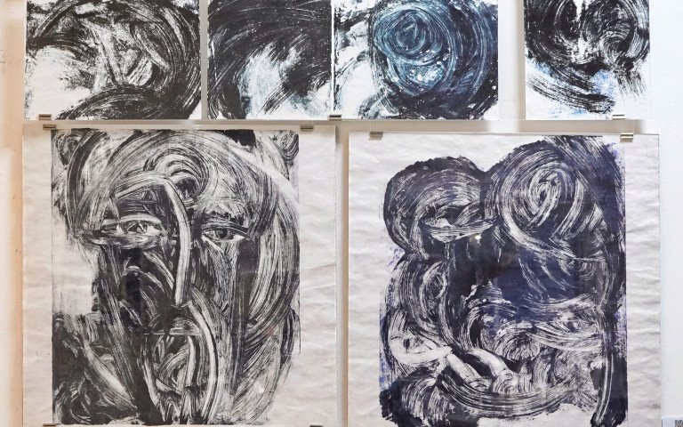 13 чорно-білих монотипів темної фарби на білому аркуші, що нагадують хмари, очі та лик Христа.