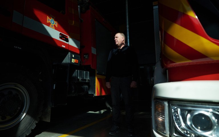 Чоловік між пожежними машинами.