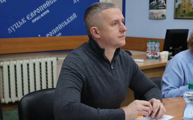 чоловік у сірому одязі сидить за столом
