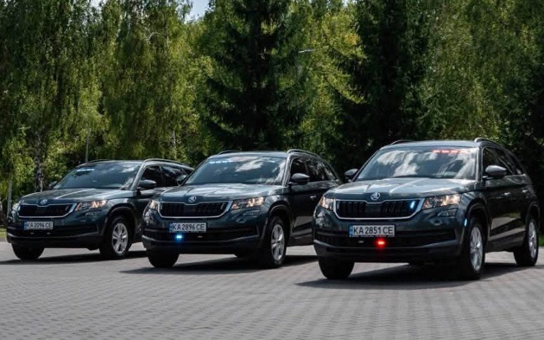 Три чорні автомобілі біля прапору України
