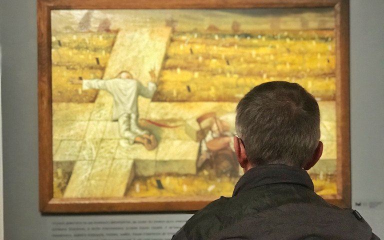 чоловік у музеї дивиться на картину Миколи Кумановського