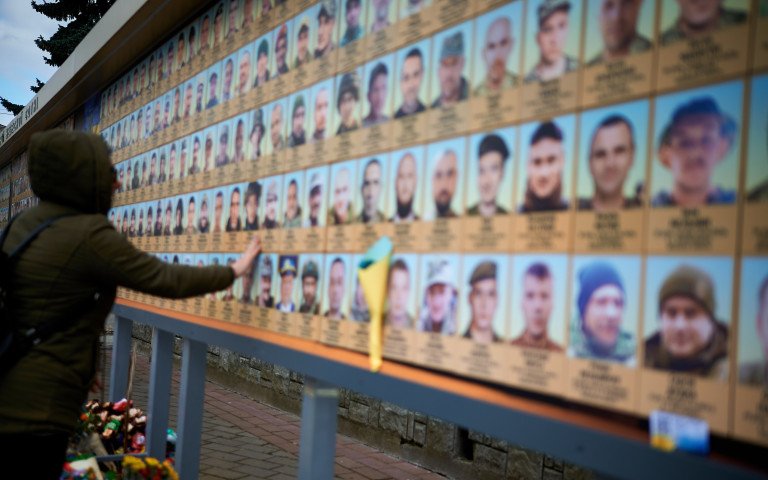 жінка біля стенду памяті героїв