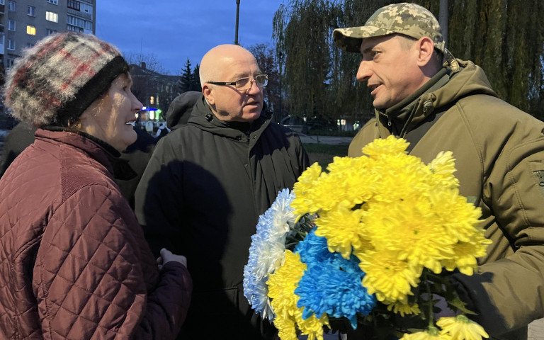 Військовослужбовець з квітами спілкується з чоловіком та жінкою