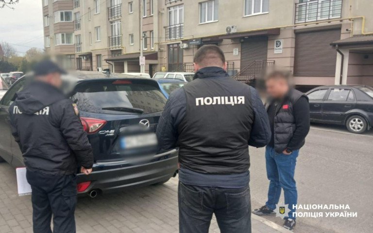 полвцейські стоять біля автомобіля.