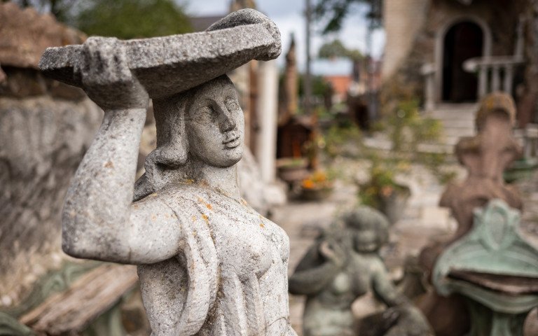 Скульптура жінки, що тримає тацю на голові. На фоні подвір'я будинку скульптора Миколи Голованя.