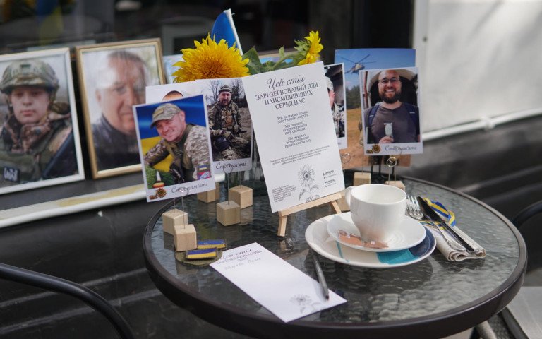 сервірований столик у кафе з портретами загиблих воїнів
