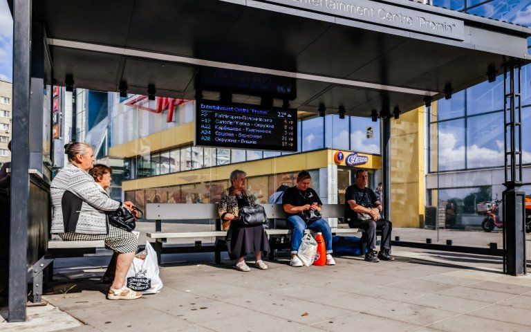 люди сидять на зупинці