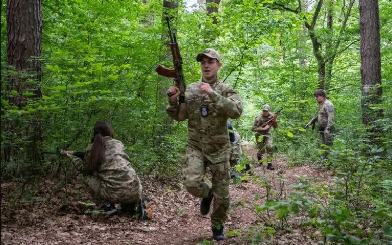 хлопець біжить із автоматом у лісі