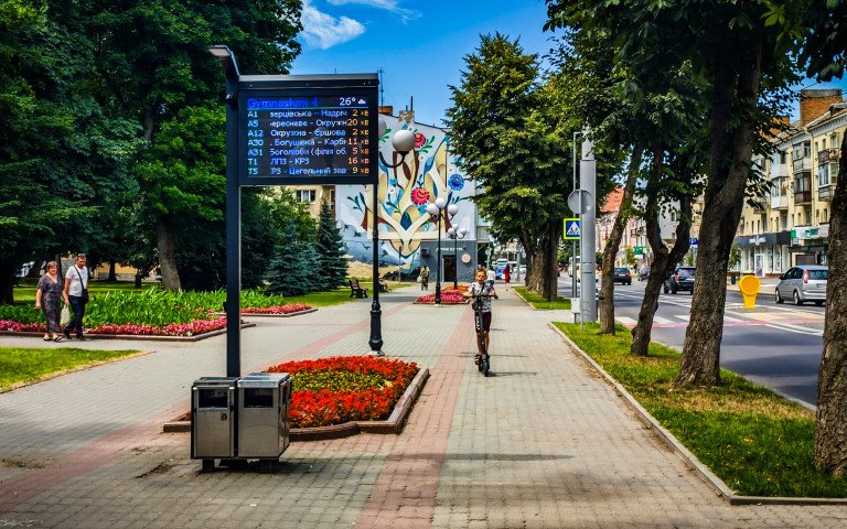 Дитина на самокаті на проспекті Волі у Луцьку біля будинку зі стінописом