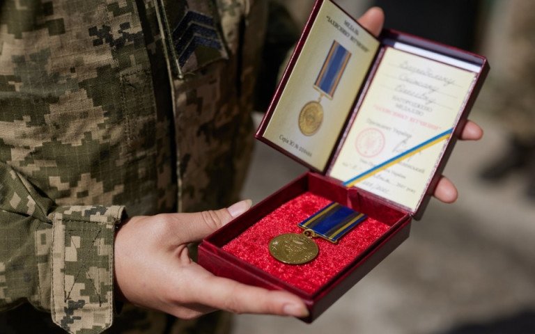 нагородна медаль та посвідчення до нього в руках військового