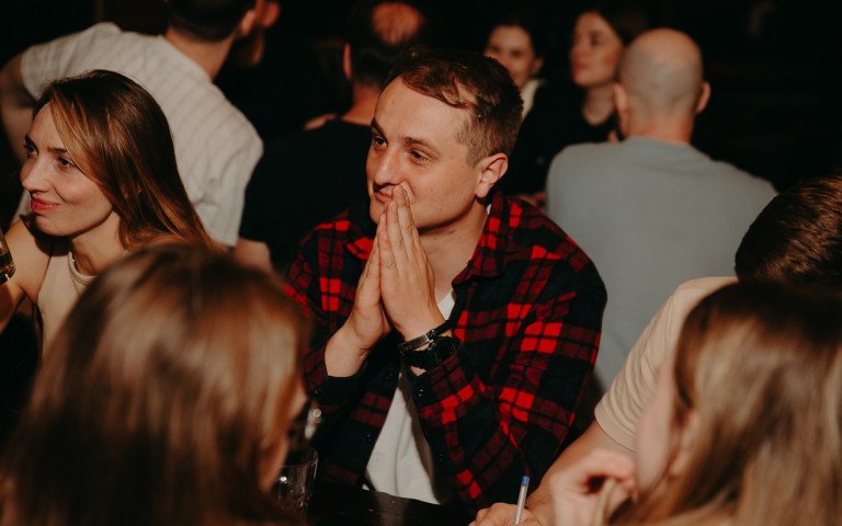 Молодий чоловік сидить за столом у компанії партнерів по команді.